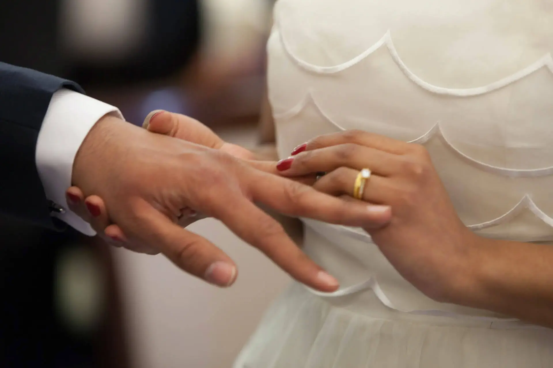 A man and woman are holding hands while wearing wedding rings.